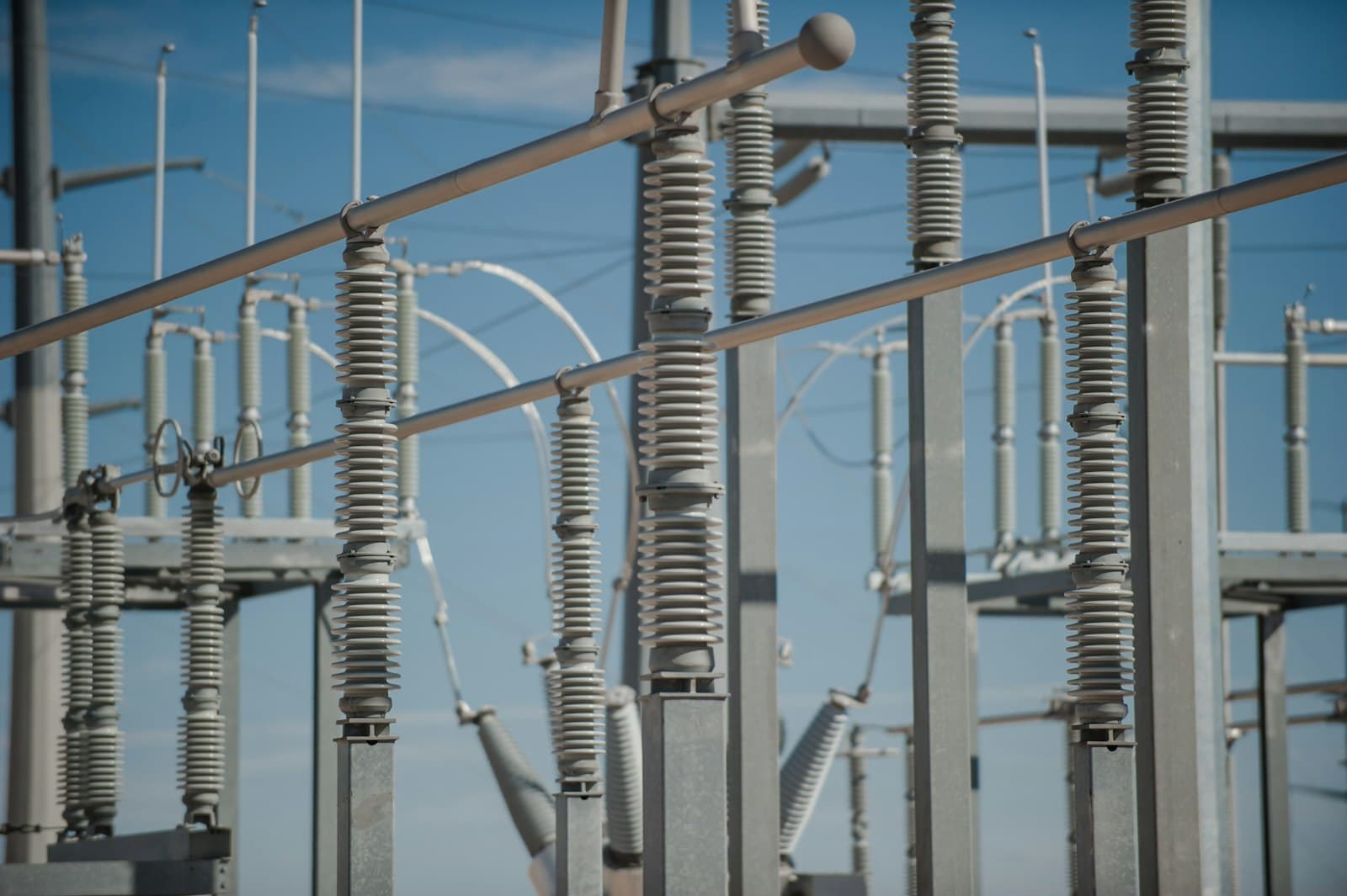 Insulators and bus work inside a substation against a blue sky