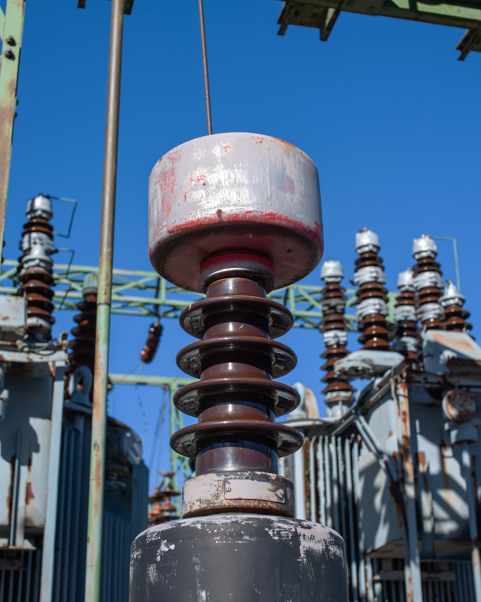 Insulators and a bushing at a substation, photographed close against a blue sky