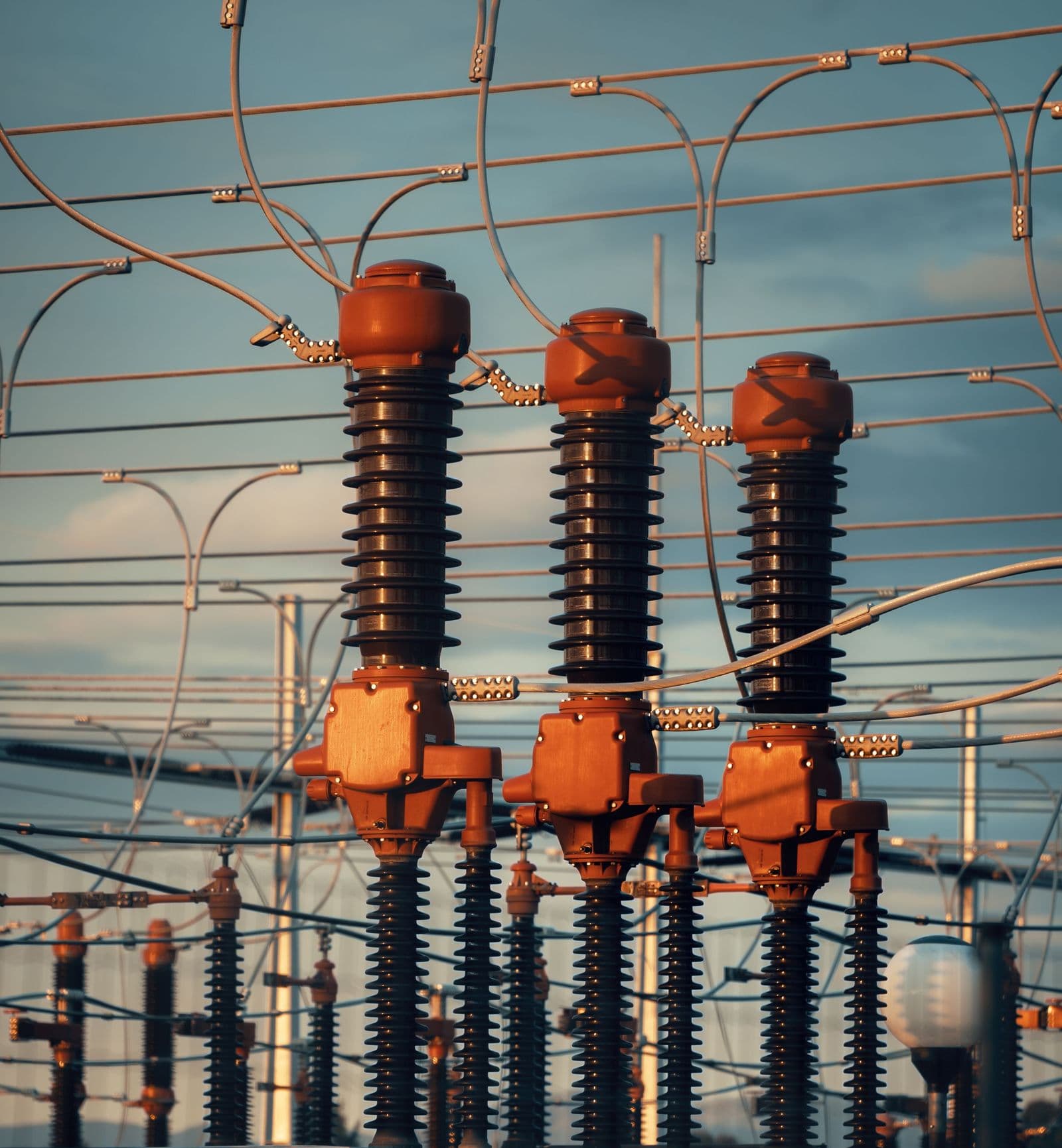 Three bushings on a substation breaker in low evening light