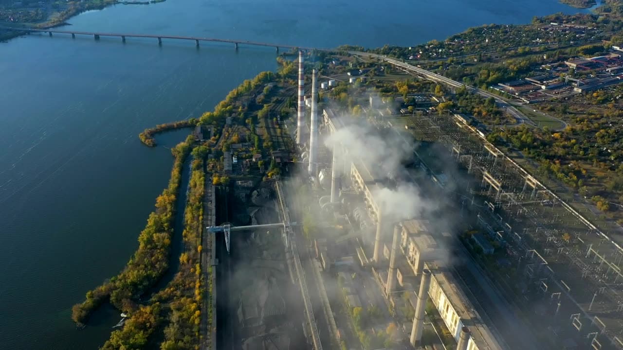 Aerial view of a power plant beside a river with its switchyard