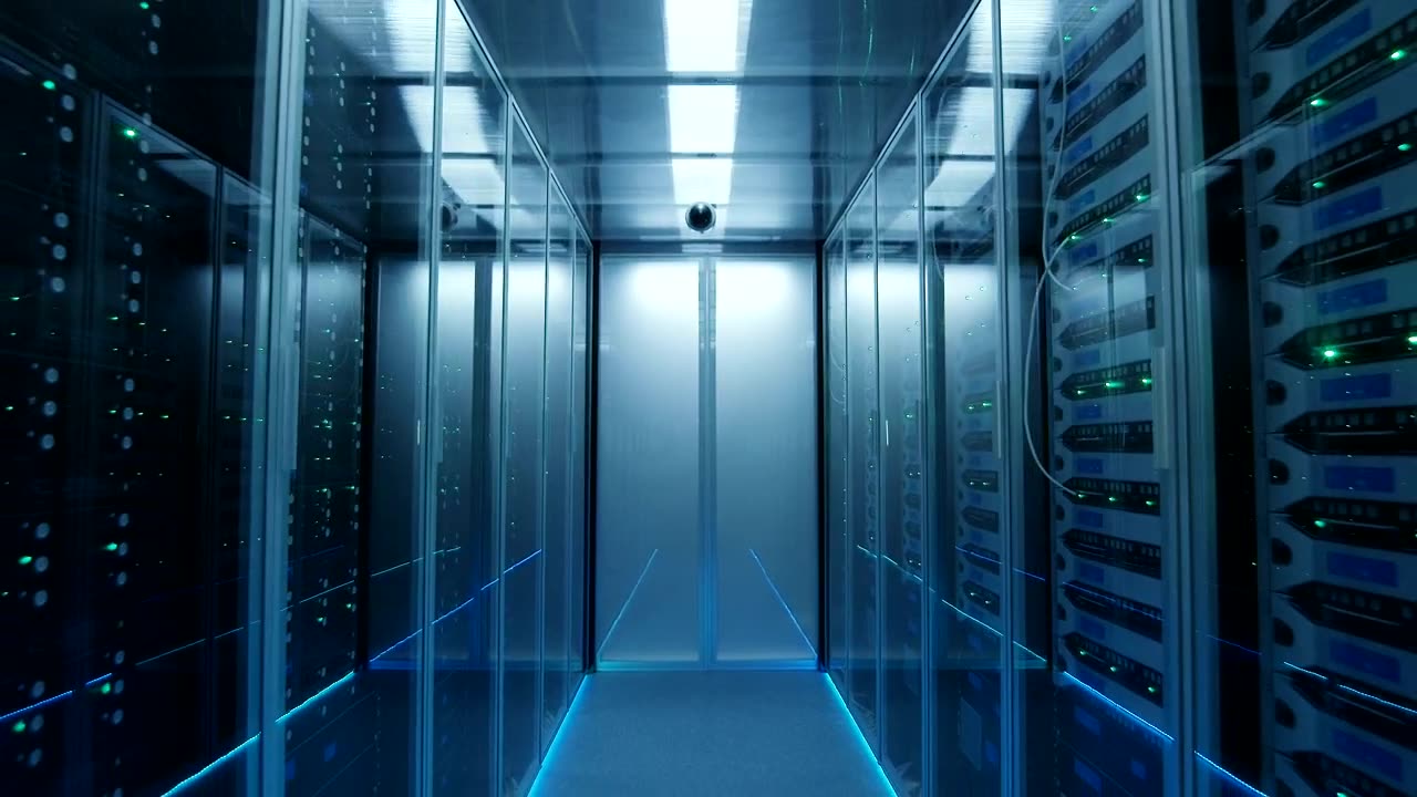 A data hall corridor between two rows of server cabinets, lit from above
