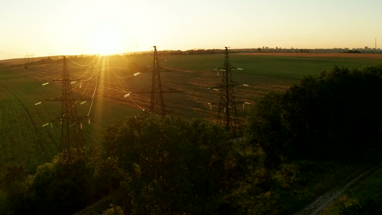 Transmission lines crossing farmland at sunset
