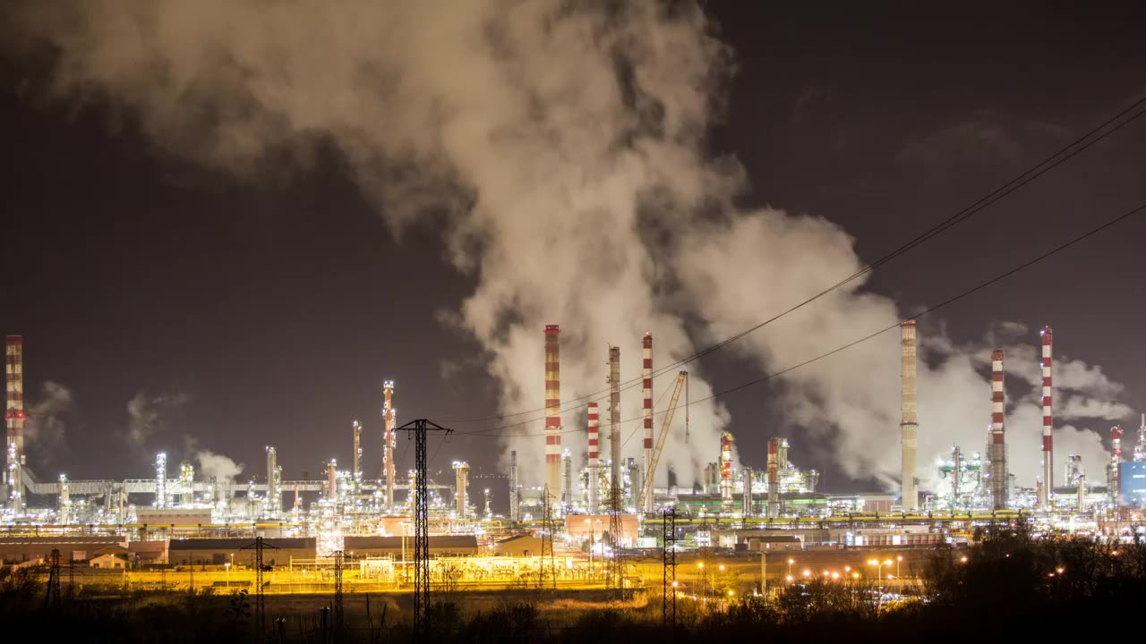Petrochemical plant lit up at night with steam rising from the stacks