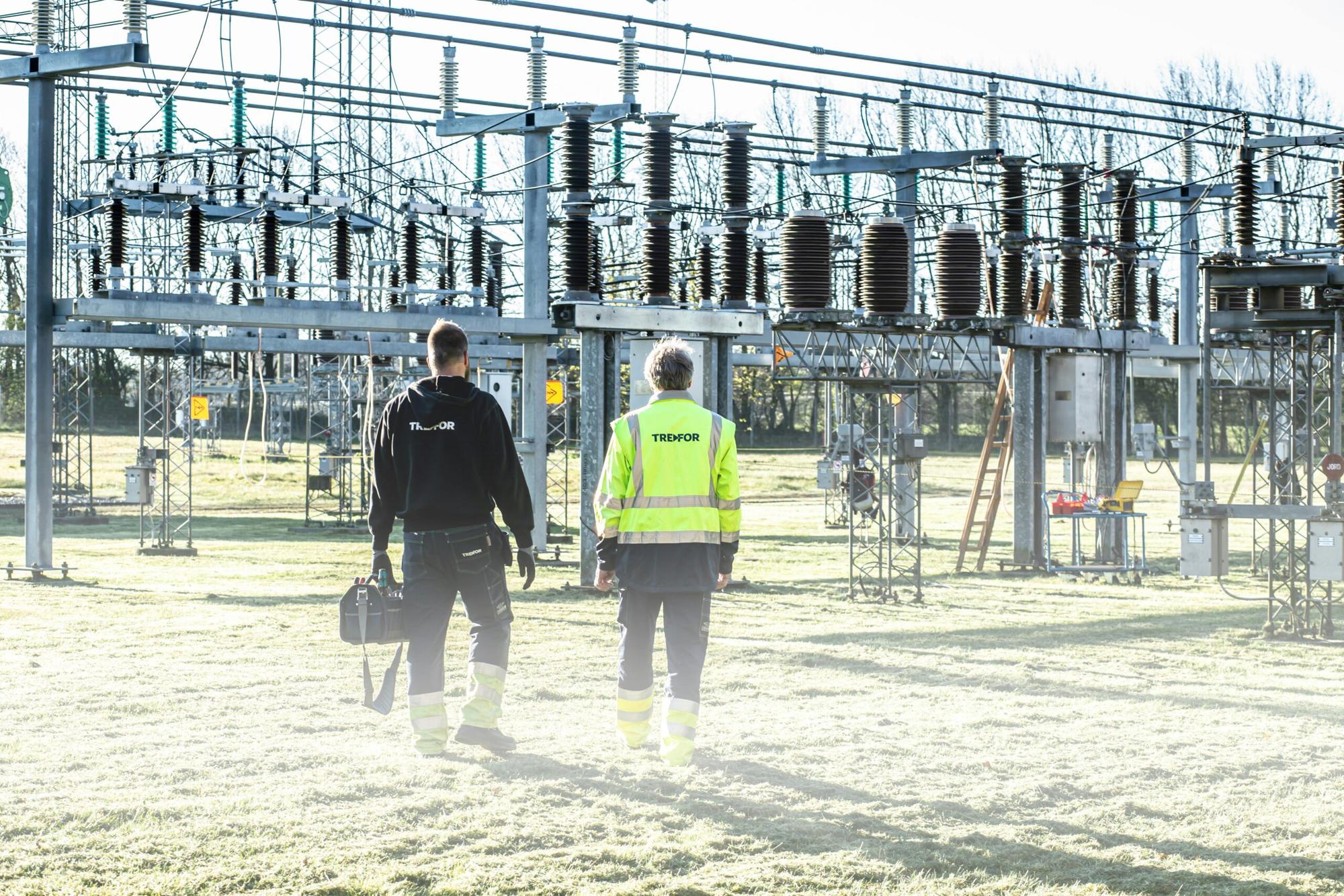 Two field workers walking through an electrical substation
